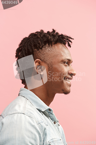 Image of The happy business Afro-American man standing and smiling against pink background. Profile view.