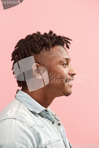 Image of The happy business Afro-American man standing and smiling against pink background. Profile view.