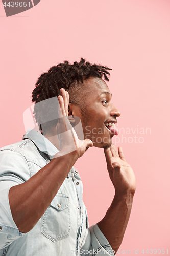 Image of The crazy business Afro-American man standing and wrinkle face pink background. Profile view.