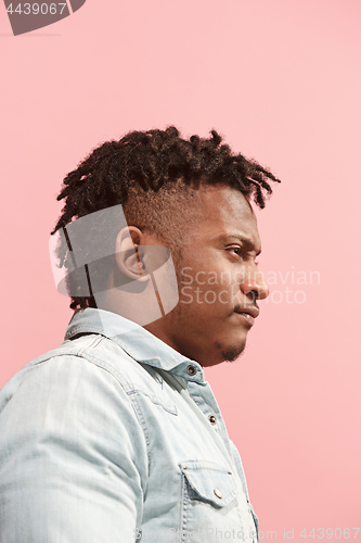 Image of The suspicious business Afro-American man standing and suspiciously looking against pink background. Profile view.