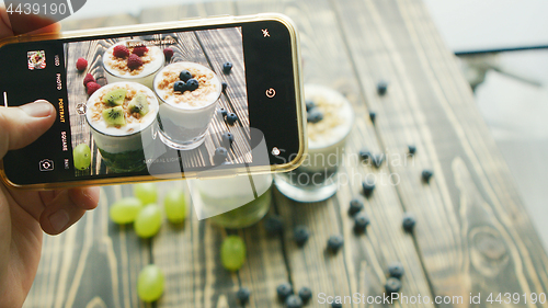 Image of Crop hand taking photo of fresh desserts