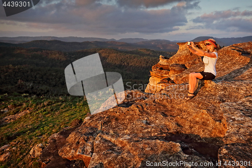 Image of Woman taking a selfie with phone in mountain landscape