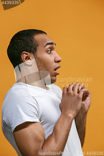 Image of Doubtful Afro-American man is looking frightenedly against orange background