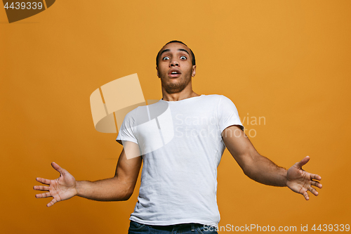 Image of The young attractive man looking suprised isolated on orange