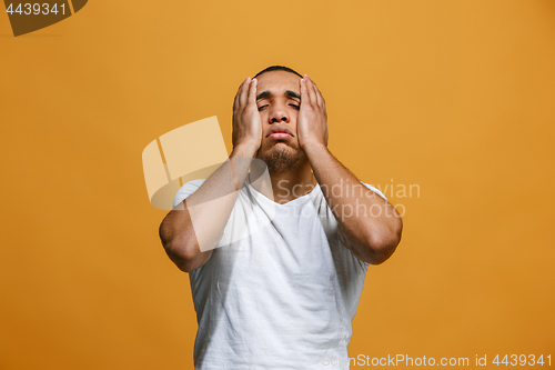 Image of Man having headache. Isolated over orange background.