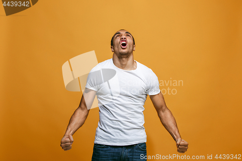 Image of The young emotional angry man screaming on orange studio background