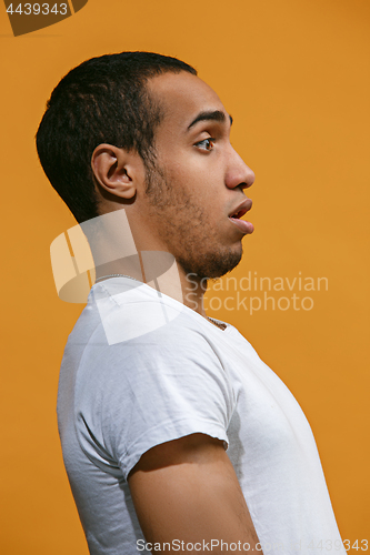 Image of Doubtful Afro-American man is looking frightenedly against orange background