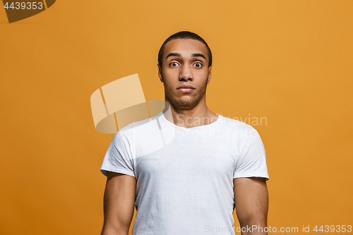 Image of The young attractive man looking suprised isolated on orange