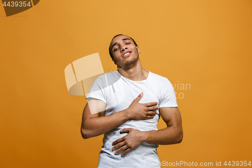 Image of The happy businessman standing and smiling against orange background.