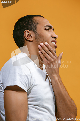 Image of Sad Afro-American man is having toothache. against orange background