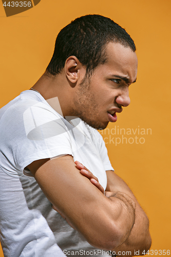 Image of Angry Afro-American man is looking serious against orange background