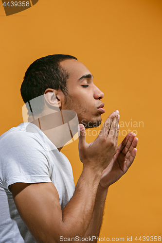 Image of Lovely Afro-American man is making air kiss against orange background