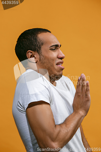 Image of Disgust Afro-American man is looking disgustingly against orange background