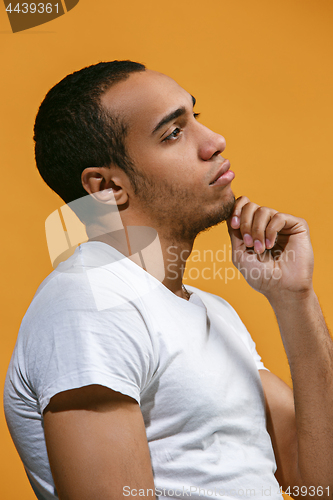 Image of Thoughtful Afro-American man is looking thoughtfully against orange background