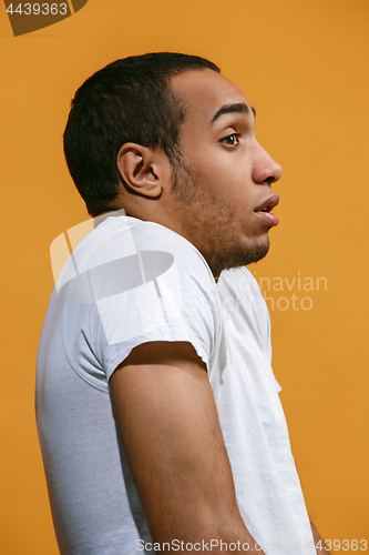 Image of Frustrated Afro-American man is looking frightenedly against orange background