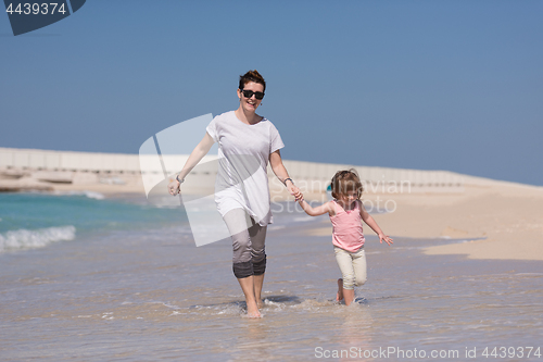 Image of mother and daughter running on the beach