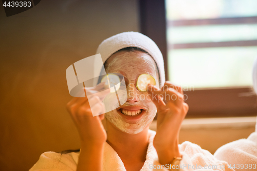 Image of woman is getting facial clay mask at spa