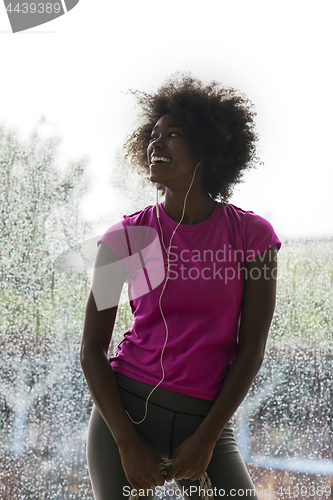 Image of portrait of young afro american woman in gym while listening mus