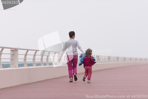 Image of mother and cute little girl on the promenade by the sea