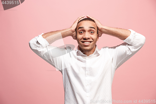 Image of The young attractive man looking suprised isolated on pink