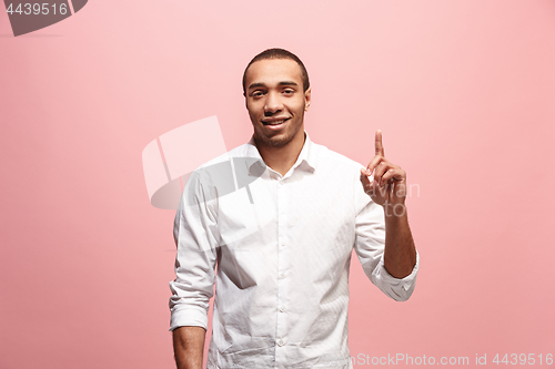 Image of The happy business man point up, half length closeup portrait on pink background.