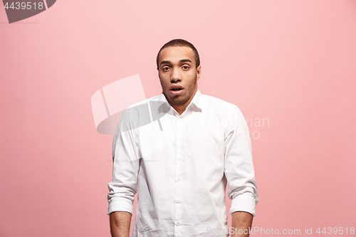 Image of The young attractive man looking suprised isolated on pink