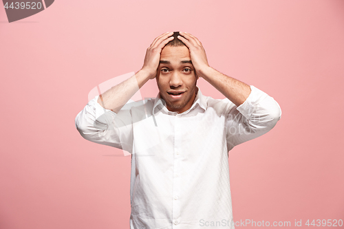 Image of The young attractive man looking suprised isolated on pink