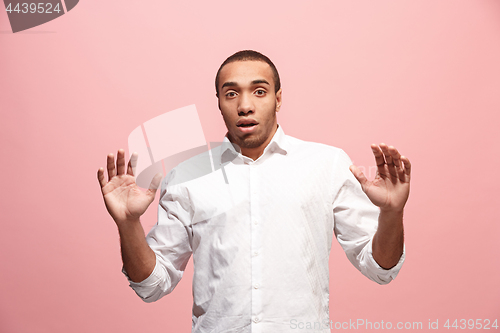 Image of The young attractive man looking suprised isolated on pink