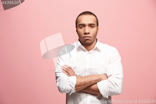 Image of The serious businessman standing and looking at camera against pink background.