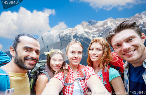 Image of friends with backpack taking selfie over mountains