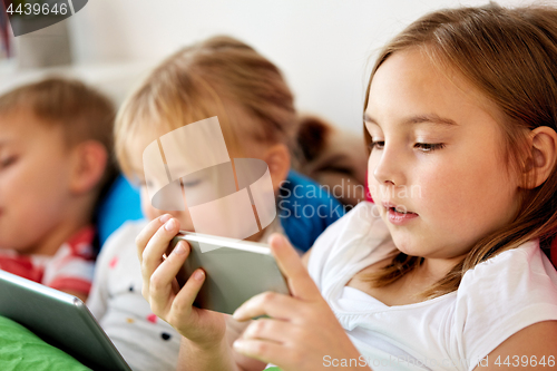 Image of little kids with smartphone in bed at home