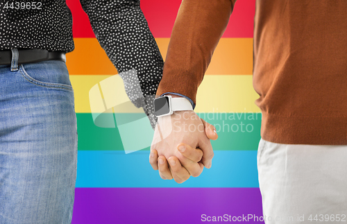 Image of close up of male gay couple hands with smartwatch