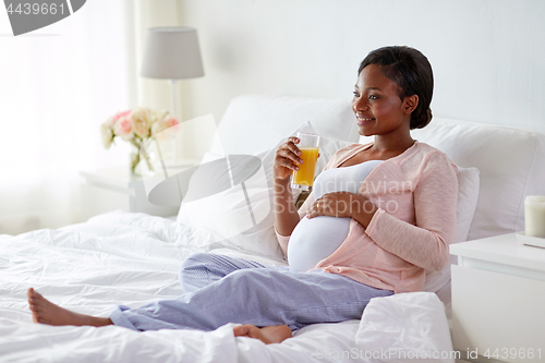 Image of pregnant woman drinking orange juice in bed