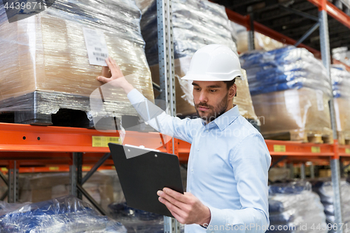 Image of businessman in helmet with clipboard at warehouse