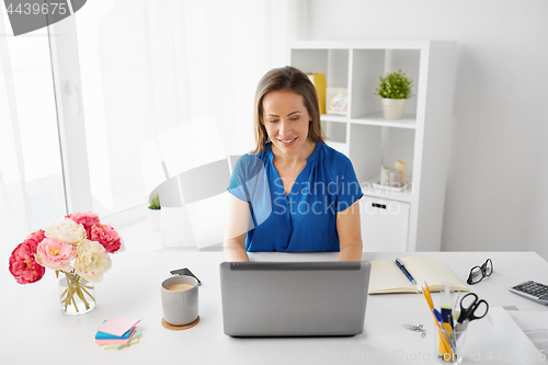 Image of happy woman with laptop working at home or office