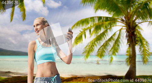 Image of woman with smartphone doing sports over beach