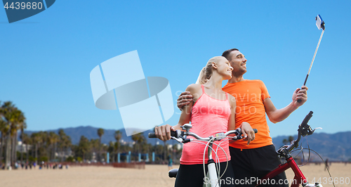 Image of couple with bicycle and smartphone selfie stick