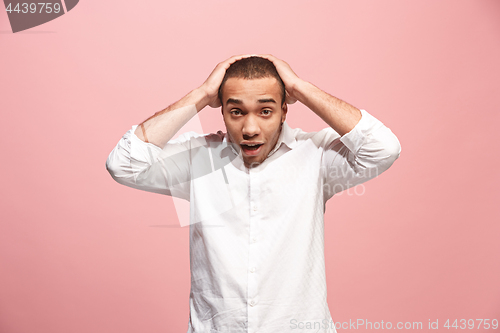 Image of The young attractive man looking suprised isolated on pink