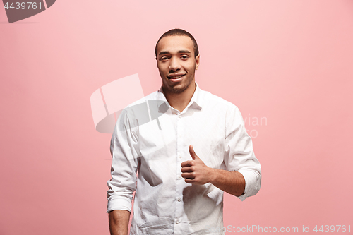 Image of The happy businessman standing and smiling against pink background.