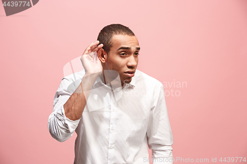 Image of The young man whispering a secret behind her hand over pink background