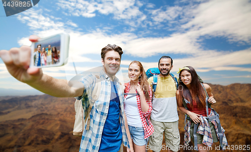 Image of friends with backpack taking selfie by smartphone