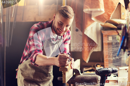 Image of carpenter working with plane and wood at workshop
