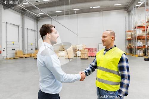 Image of worker and businessman with clipboard at warehouse