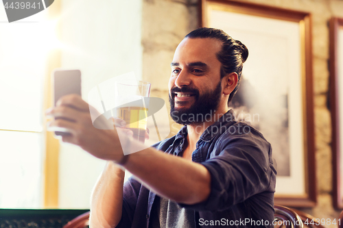 Image of man with smartphone drinking beer at bar or pub