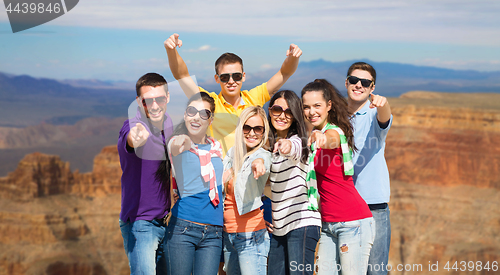 Image of happy friends pointing at you over grand canyon