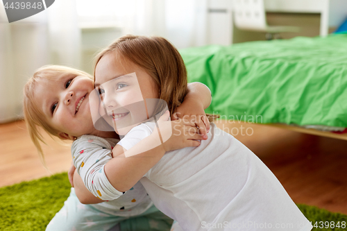 Image of happy little girls or sisters hugging at home