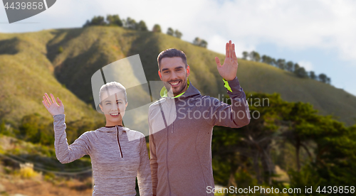 Image of smiling couple in sport clothes waving hand