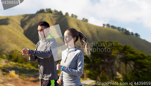 Image of couple with fitness trackers running outdoors