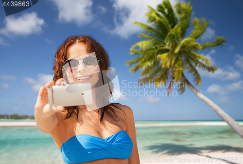 Image of woman taking selfie by smartphone on beach