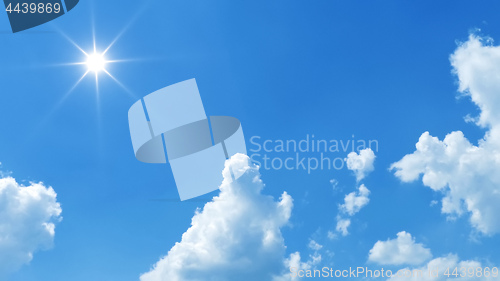 Image of blue sky with bright sun and white clouds